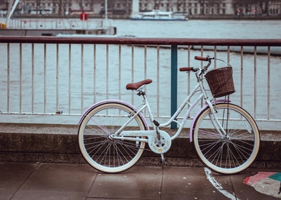 白色城市自行车，篮子停在栏杆附近